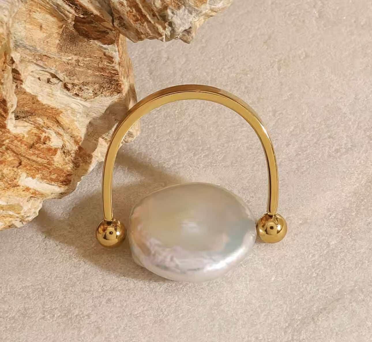 Gold-plated U-shaped ring with freshwater pearl on model hand, showcasing waterproof and hypoallergenic design.