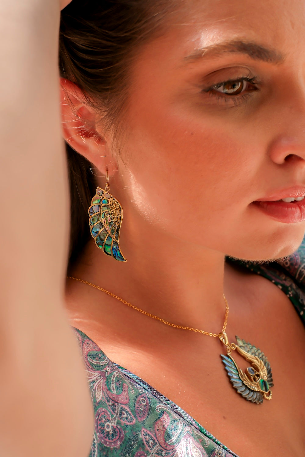 Gold-tone necklace featuring carved paua shell wings