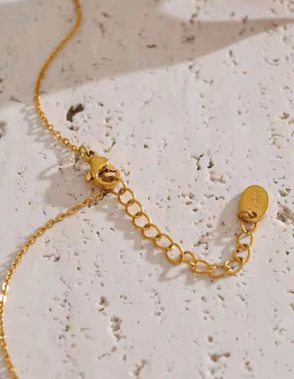 Gold chain necklace styled flat with textured stone background