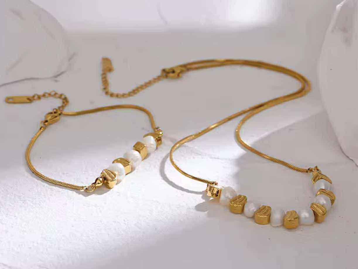 Flat lay of the Golden Hour Bracelet with matching necklace, styled with natural textures and light