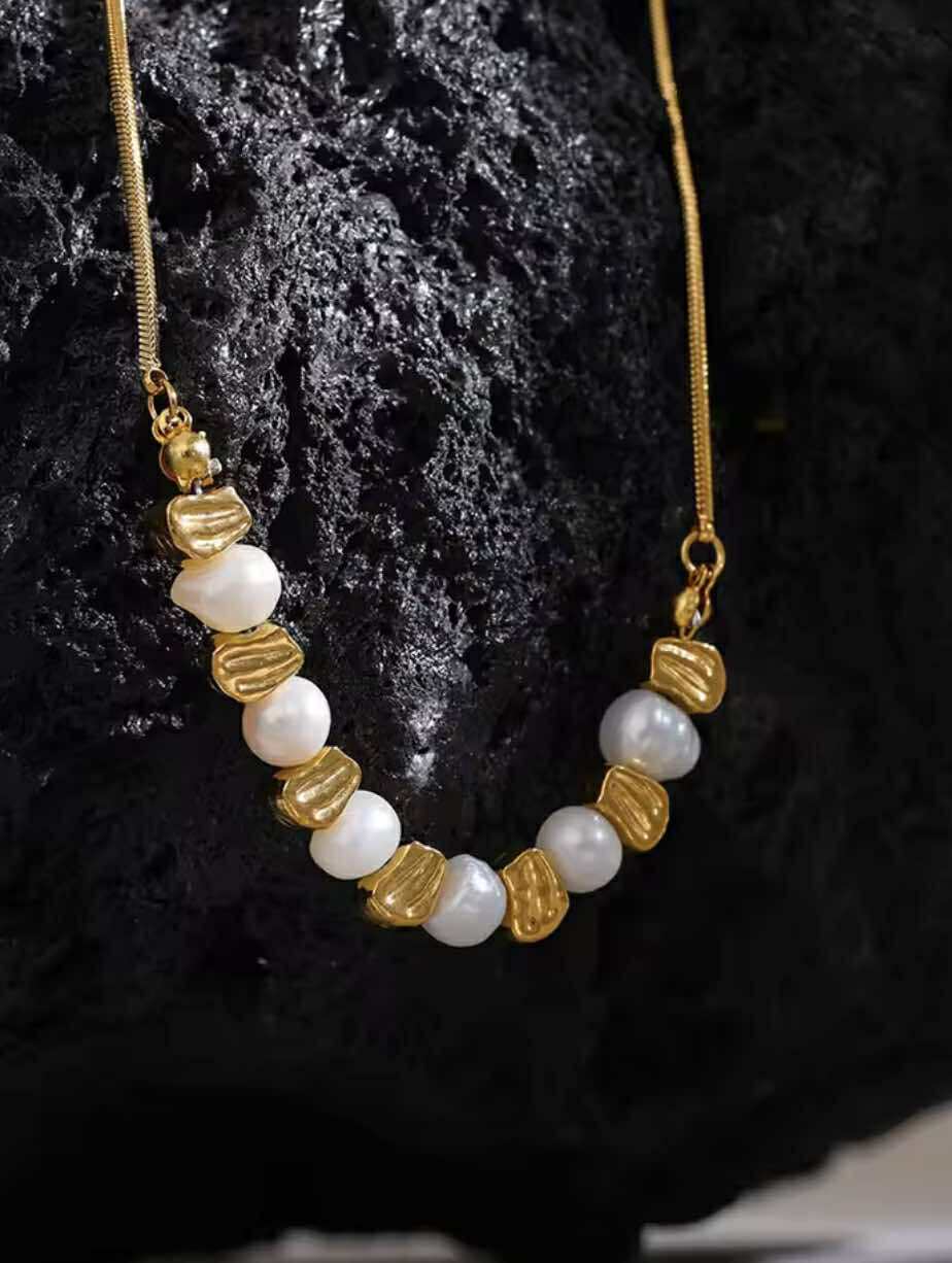 Golden Hour Necklace with freshwater pearls and vintage gold stainless steel beads, styled on a neutral-toned backdrop.