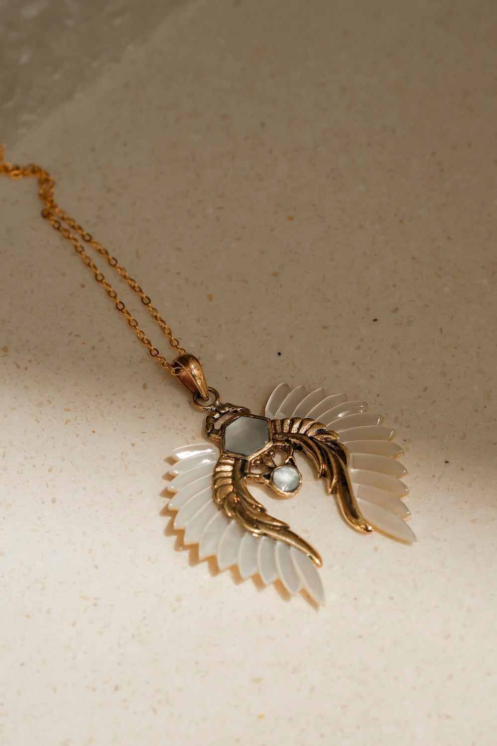 Hand-carved shell pendant with iridescent wings on gold chain
