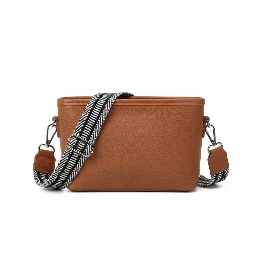 A brown pebbled leather crossbody bag with a wide, woven black and white striped shoulder strap, shown against a plain white background.