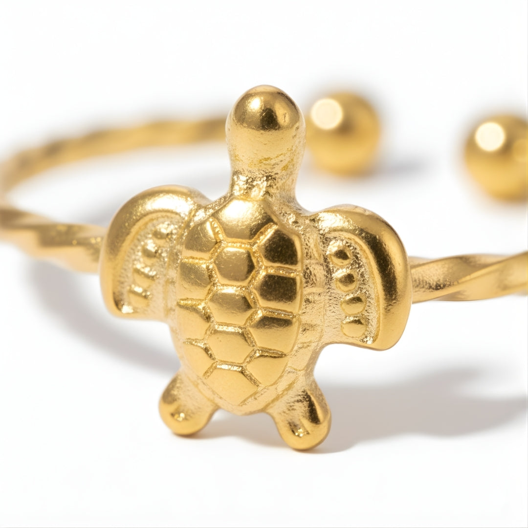 Close-up of the Isla Turtle Ring featuring a detailed gold-plated sea turtle charm on a twisted rope-textured band.