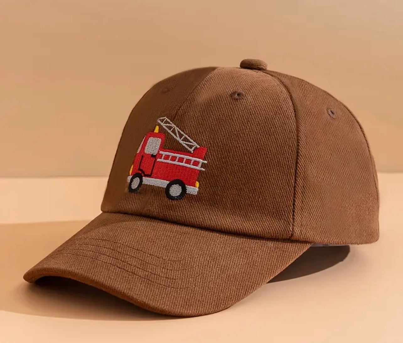 Close-up of the brown firetruck design on the hat, highlighting the vibrant colors and intricate stitching