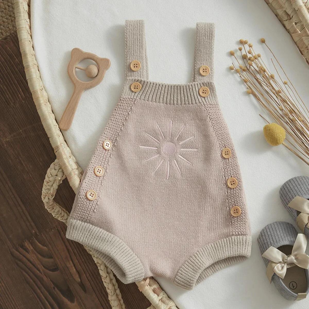 Newborn dressed in a pink knit romper, ideal for warm weather and layering during cooler months.