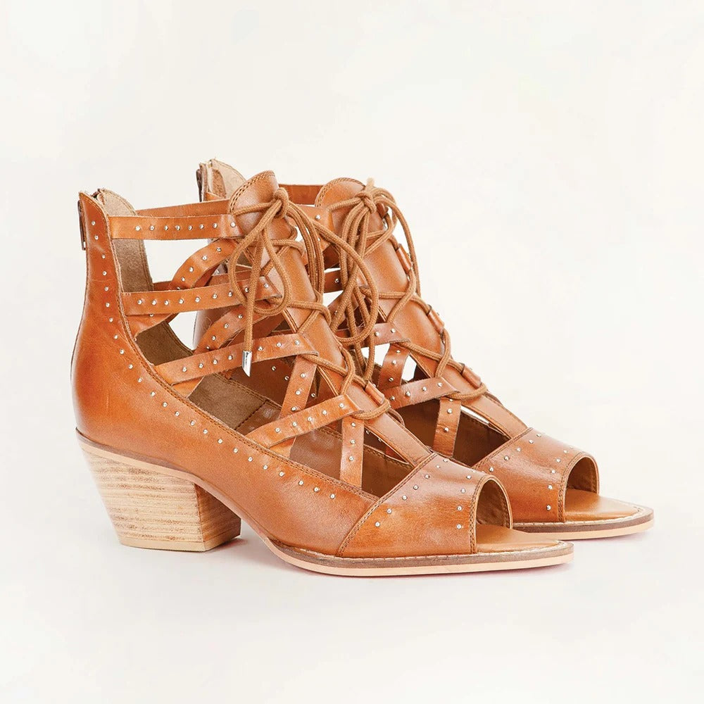 Lace Up Booties In Calfskin from House of Hide in tan calfskin leather with open toe, studded details, and stacked wooden block heel being displayed against plain white background