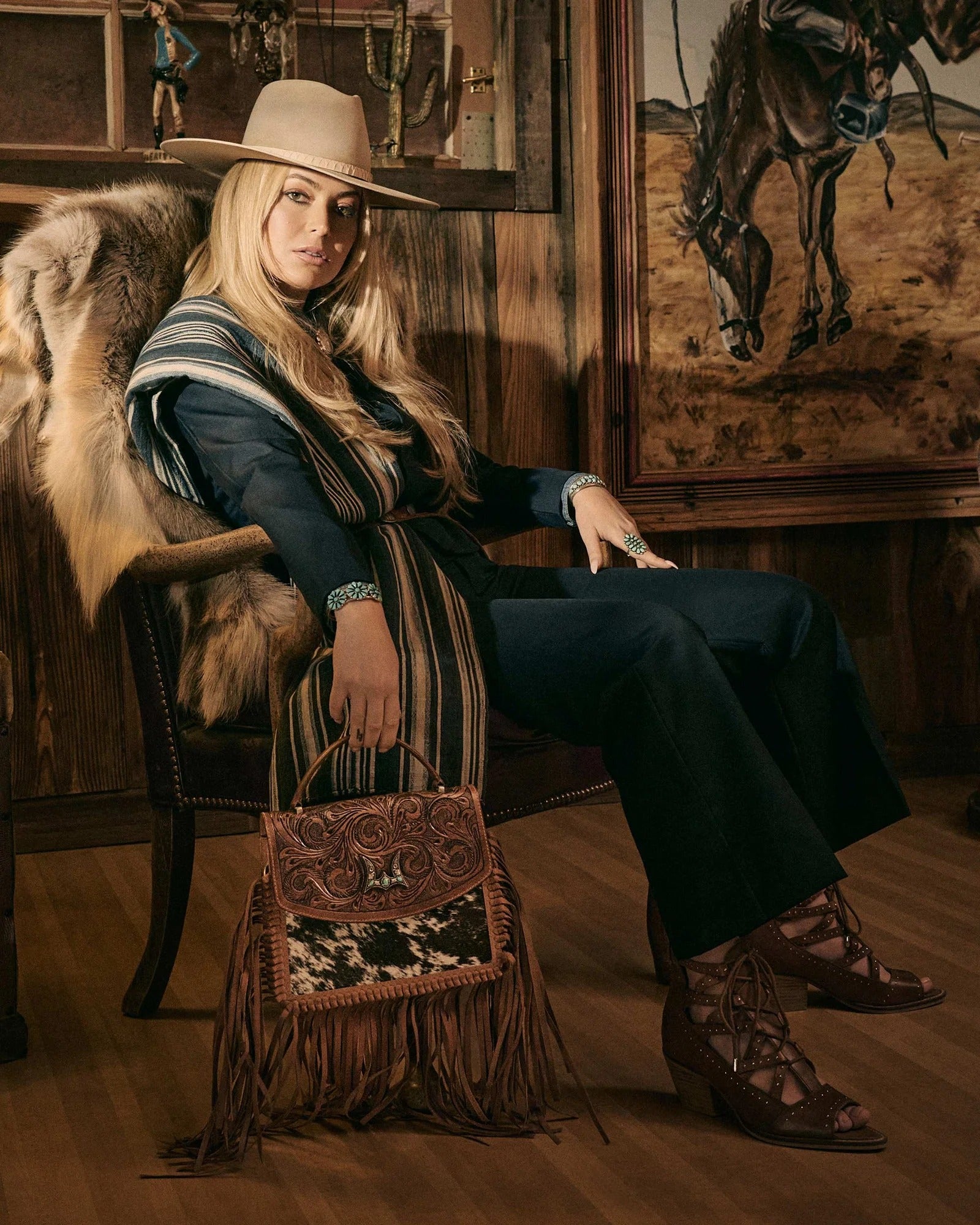 Lace Up Booties In Calfskin from House of Hide in brown calfskin leather with lace-up strappy design and decorative cutout details being worn by model in cowboy hat seated in rustic western interior