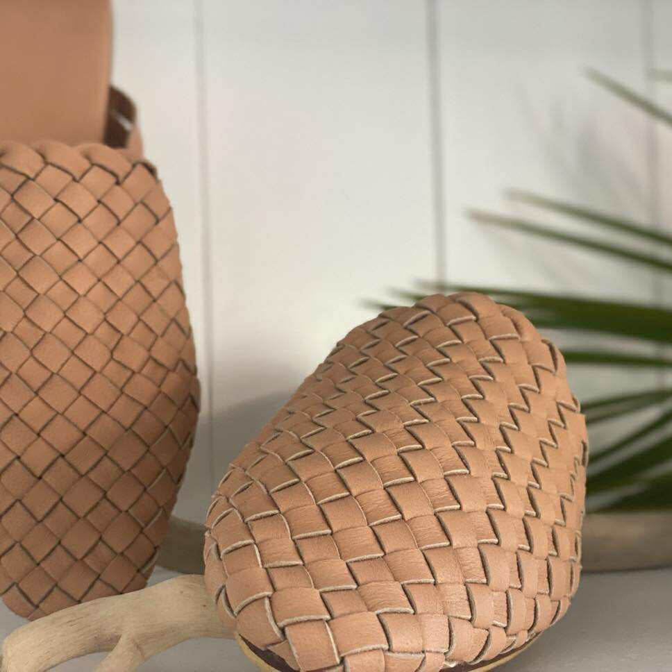 Woven pineapple-shaped object on a surface with a blurred background