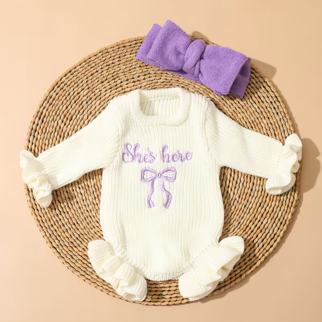 Little Darling Knit Romper Set from House of Hide in cream ribbed knit romper featuring violet embroidered bow design, ruffled cuffs and hem for extra charm, gentle on newborn skin, matching violet bow headband included on woven mat display