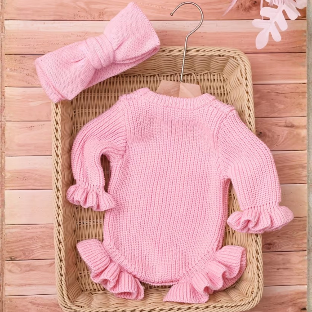 Little Darling Knit Romper Set from House of Hide in pink ribbed knit with white she's here embroidery and matching pink bow headband being styled in wicker basket on rustic wooden flooring with coordinated bow detail