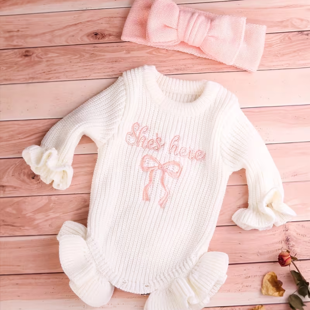 Little Darling Knit Romper Set from House of Hide in white ribbed knit with pink embroidered she's here text and decorative bow being displayed on woven straw mat with soft pink aesthetic