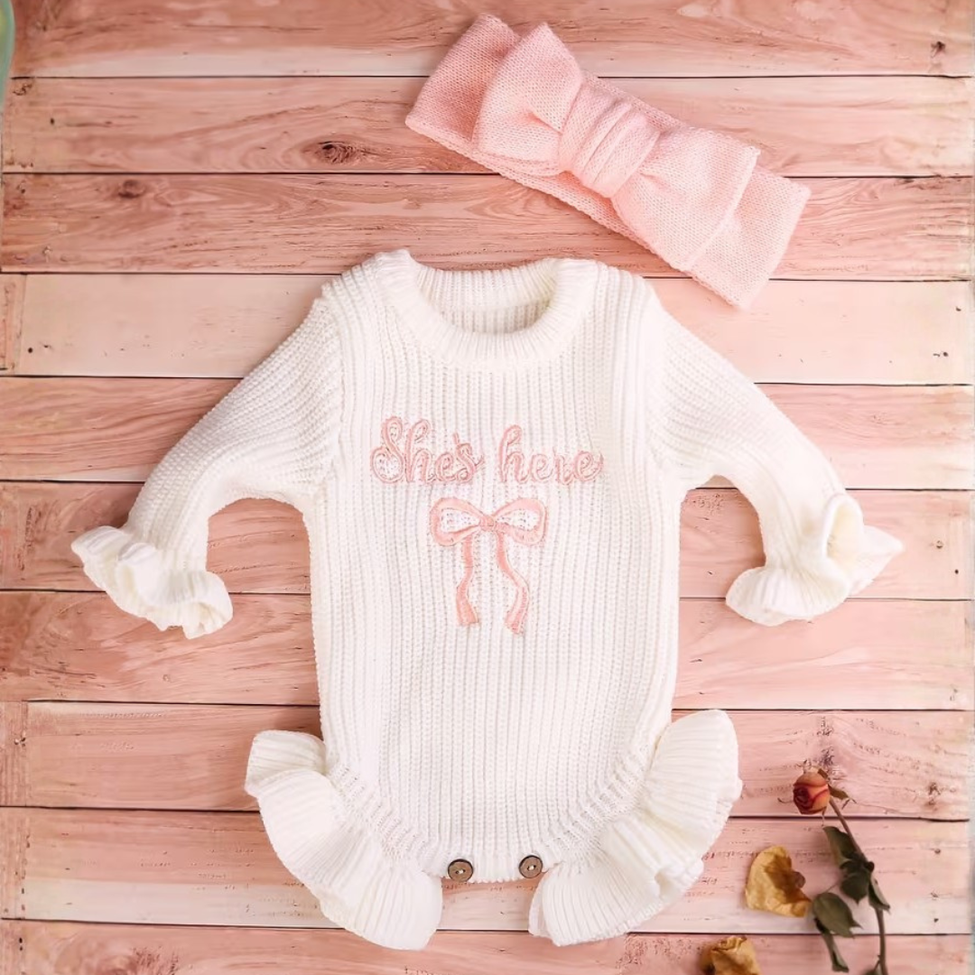 Little Darling Knit Romper Set from House of Hide in white ribbed knit long-sleeve romper with pink embroidery and matching pink pom-pom beanie being styled in woven basket on rose wood background