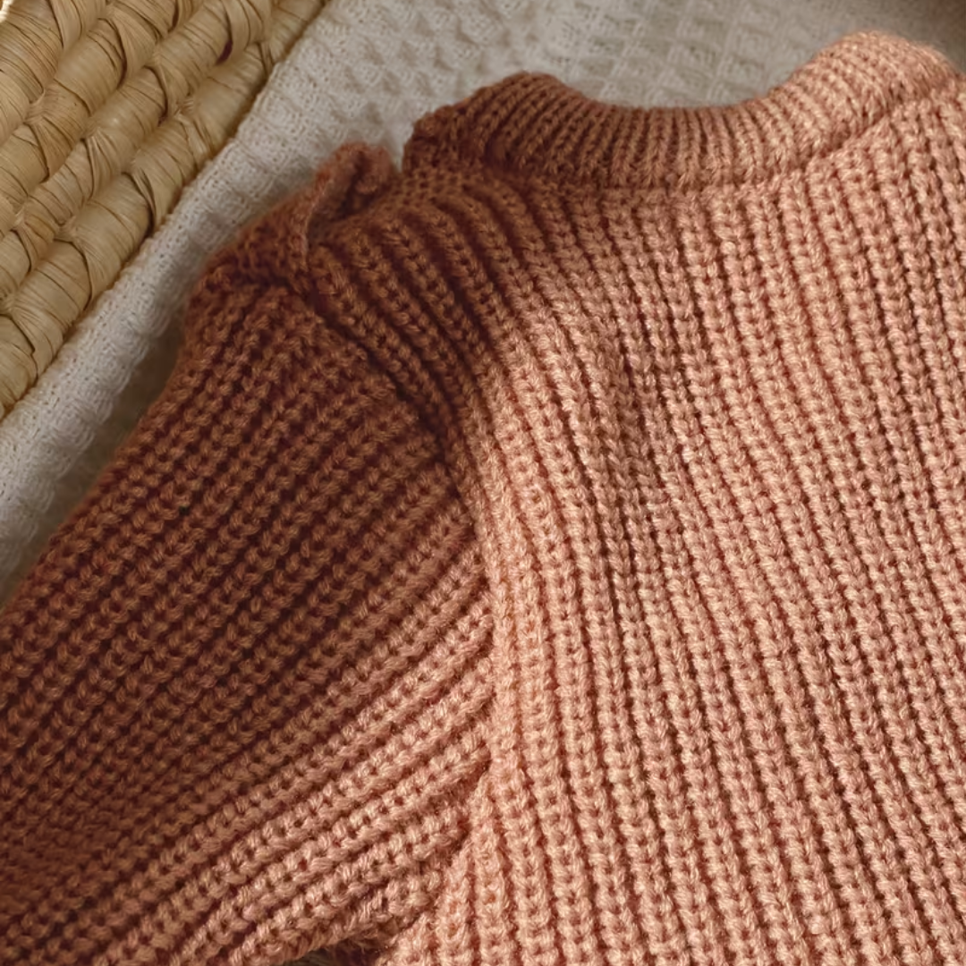Little Wrangler Knit Romper Set from House of Hide in dusty rose chunky ribbed knit with crew neck being displayed in close-up on neutral woven mat