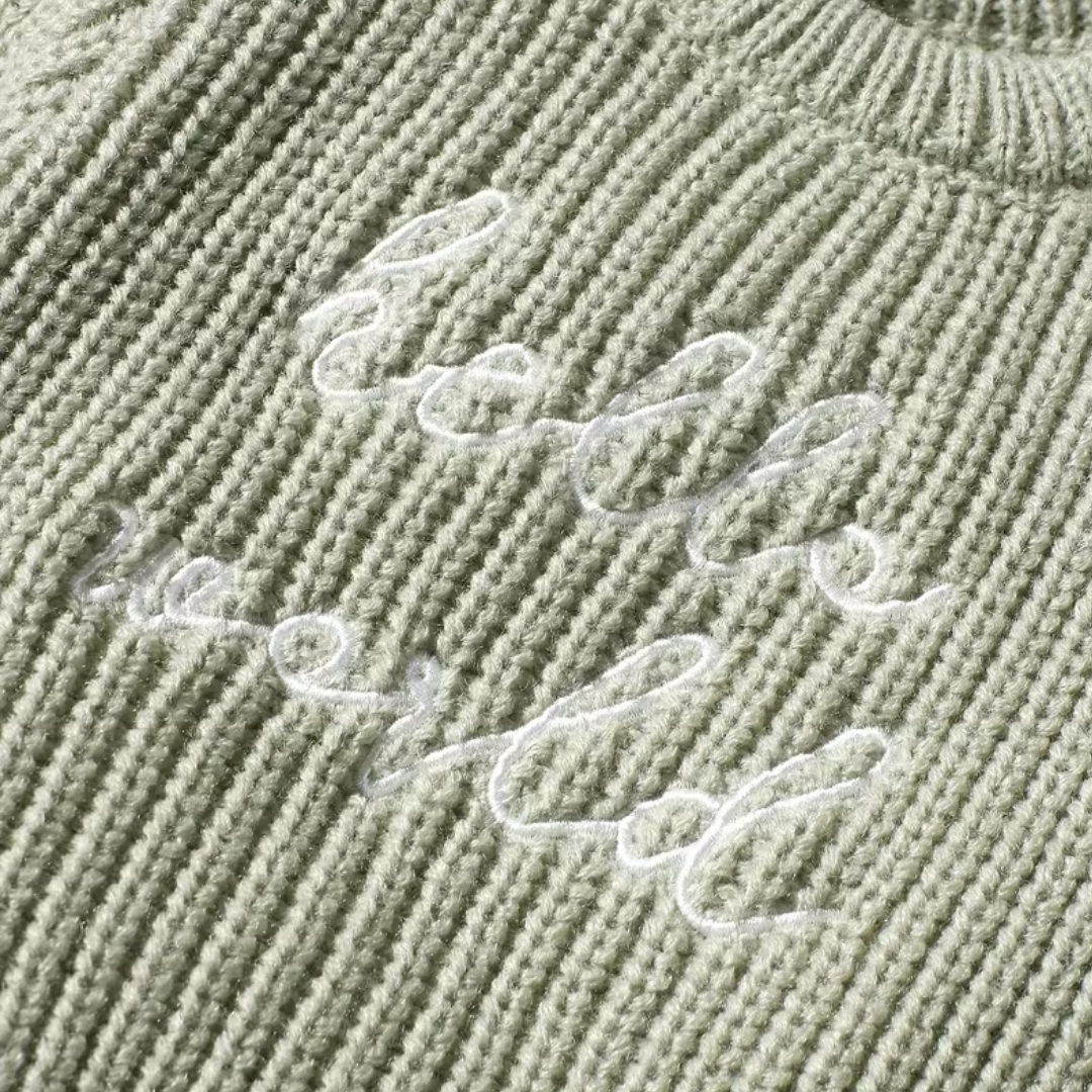 Little Wrangler Knit Romper Set from House of Hide in muted sage green ribbed knit with white cursive hello world embroidery being displayed in close-up