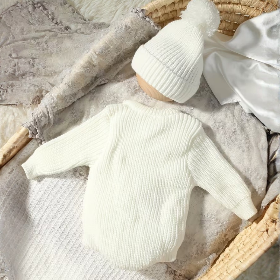 Little Wrangler Knit Romper Set from House of Hide in off-white ribbed knit romper and matching pom-pom beanie being displayed in woven basket with soft blankets