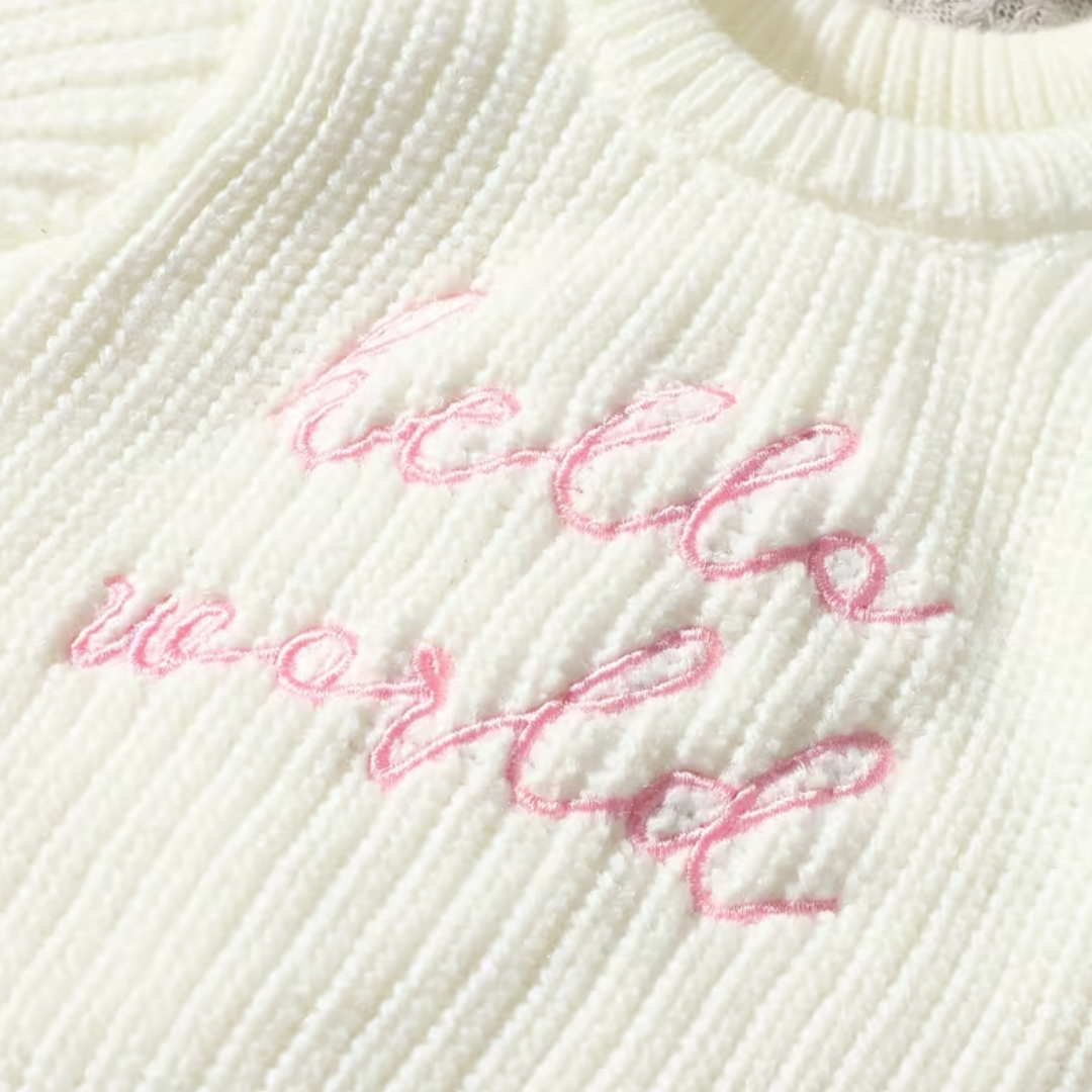 Little Wrangler Knit Romper Set from House of Hide in cream beige ribbed knit with pink cursive hello world embroidery across chest being displayed in close-up