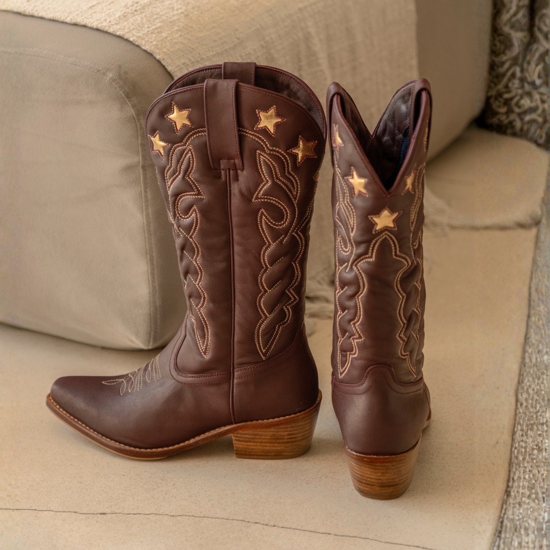 Lone Star Boots from House of Hide in dark brown leather with gold embroidered stars and western-style stitching being displayed on beige sofa