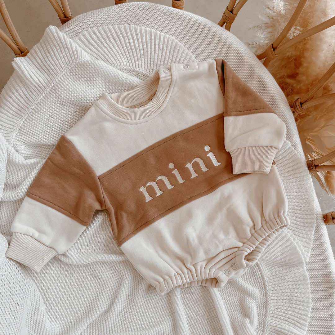 Long-sleeve bubble romper laid flat, showcasing its soft fabric and snap-button neckline for easy changing.