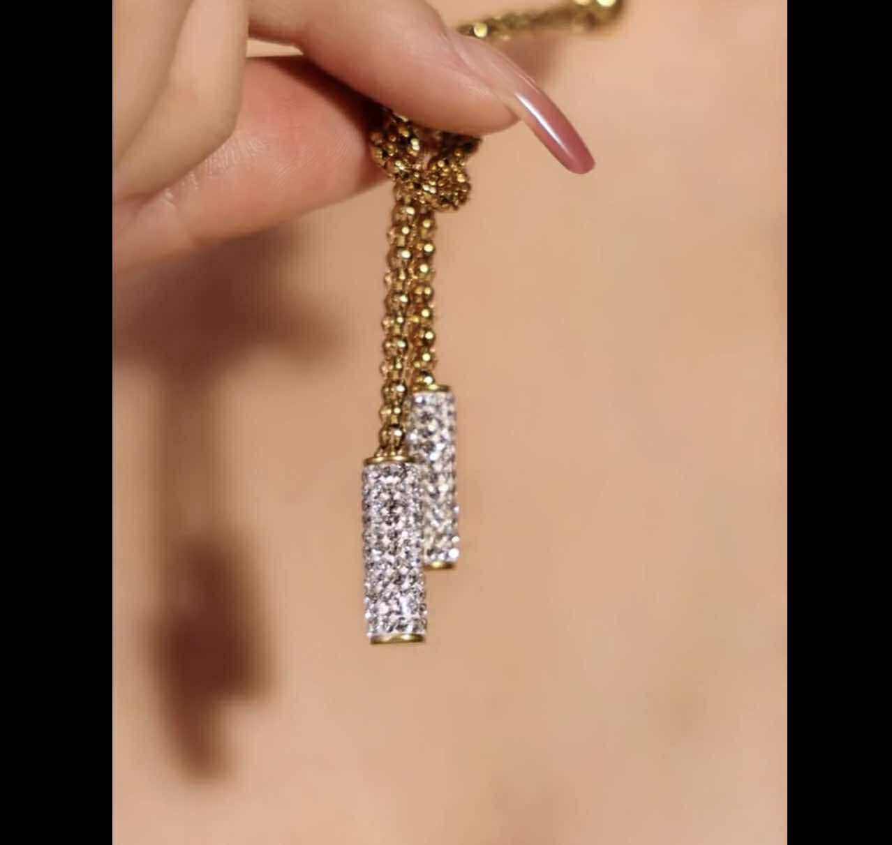 Long gold stainless steel necklace with knot detail and dual rhinestone drops.