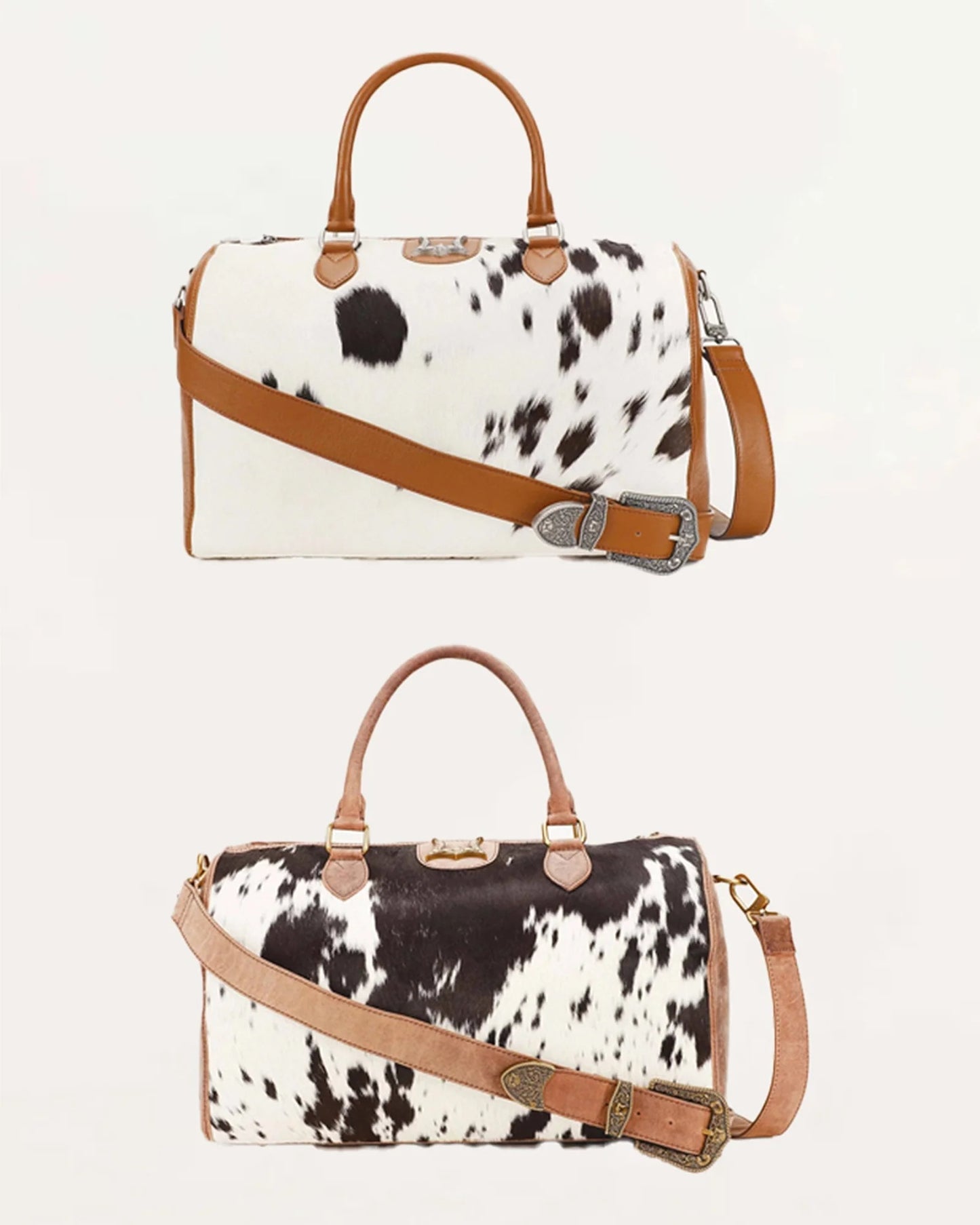 Two cowhide duffle bags with tan leather handles, trim, and straps, shown against a plain light background. The top bag is white with black spots and a silver buckle detail, while the bottom bag is black and white spotted with a tan strap.