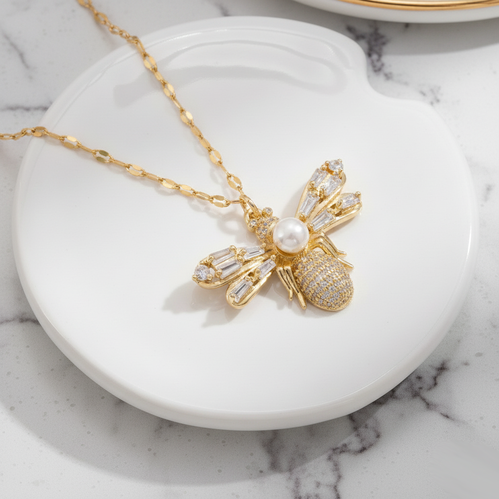 Close-up of the Luna Bee Necklace featuring a gold-plated bee pendant with crystal baguette wings and pearl centerpiece.