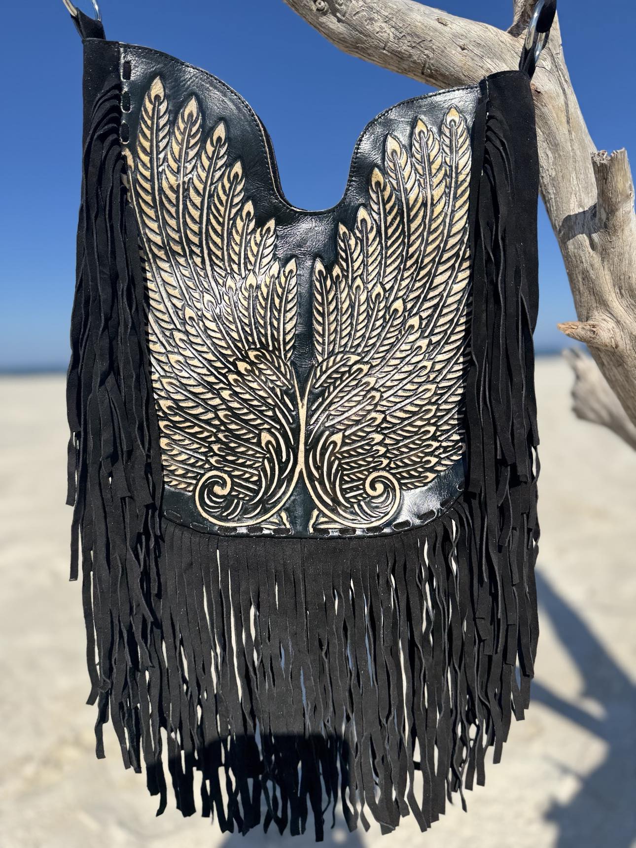Metallic navy leather fringe bag with silver wing embroidery, handwoven edges, and boho-inspired design, perfect as a crossbody or shoulder bag.