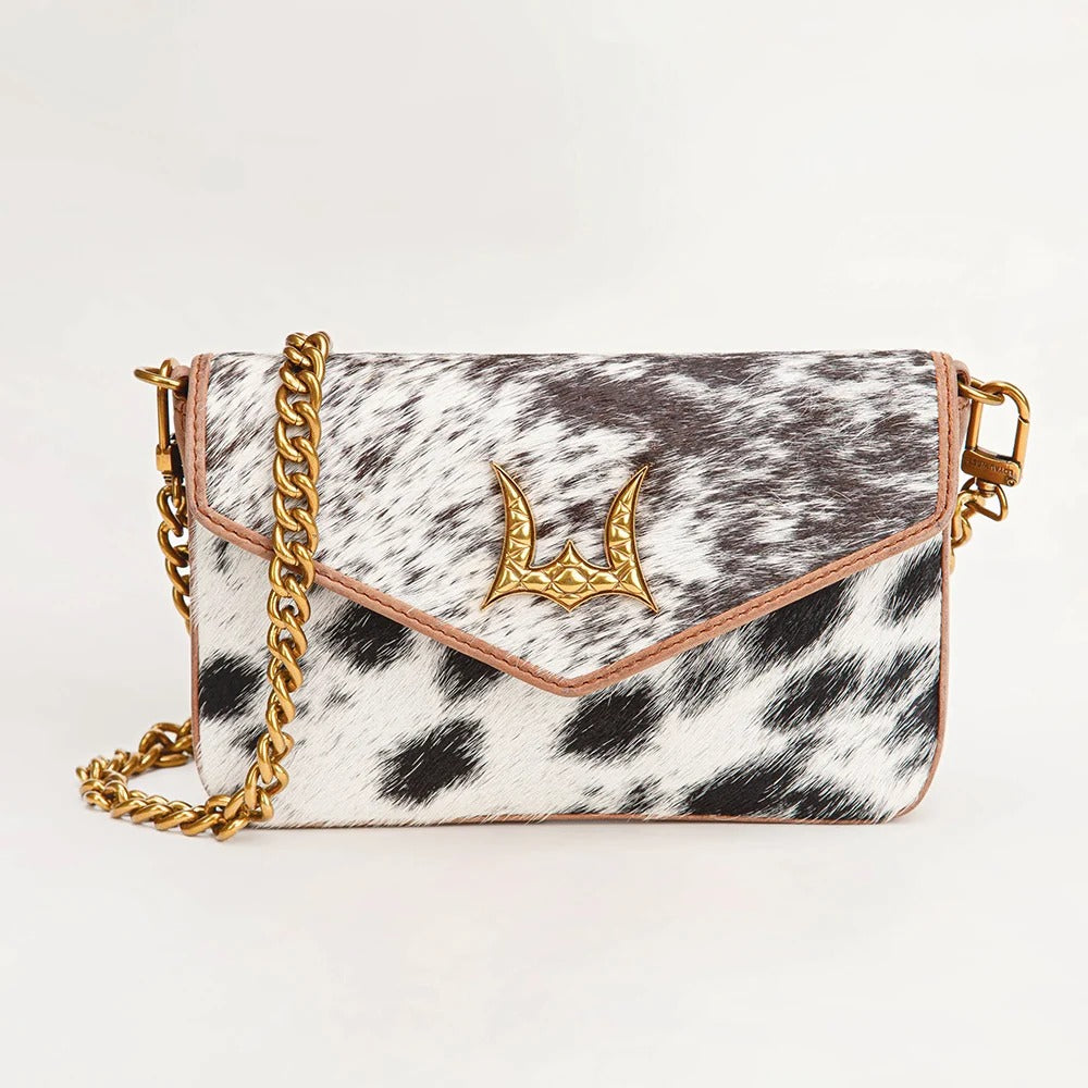 A black and white cowhide shoulder bag with a gold-tone chain strap and a decorative gold horn clasp, shown on a plain white background.