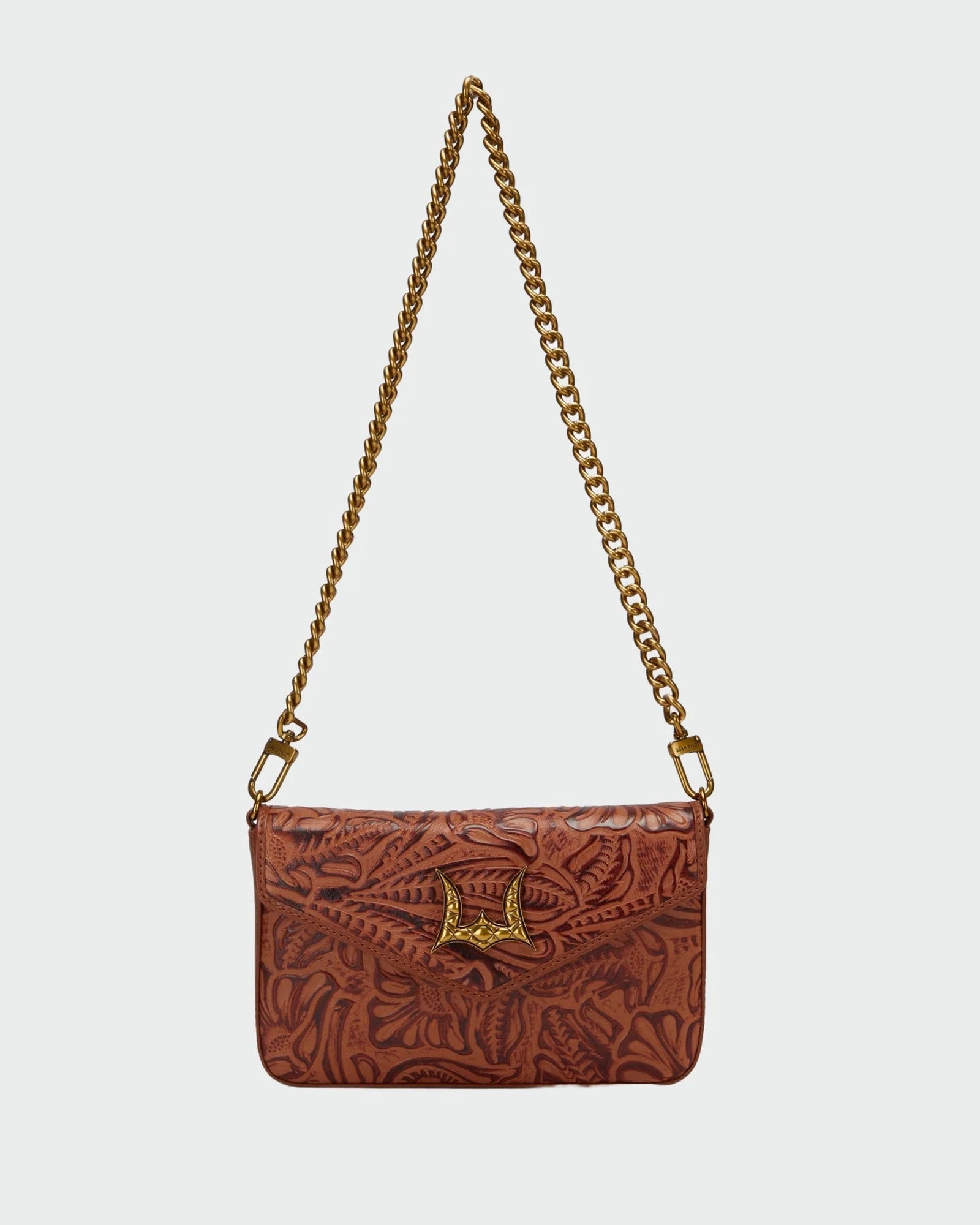 A brown tooled leather shoulder bag with a gold-tone chain strap and a decorative gold clasp, shown against a light gray background.