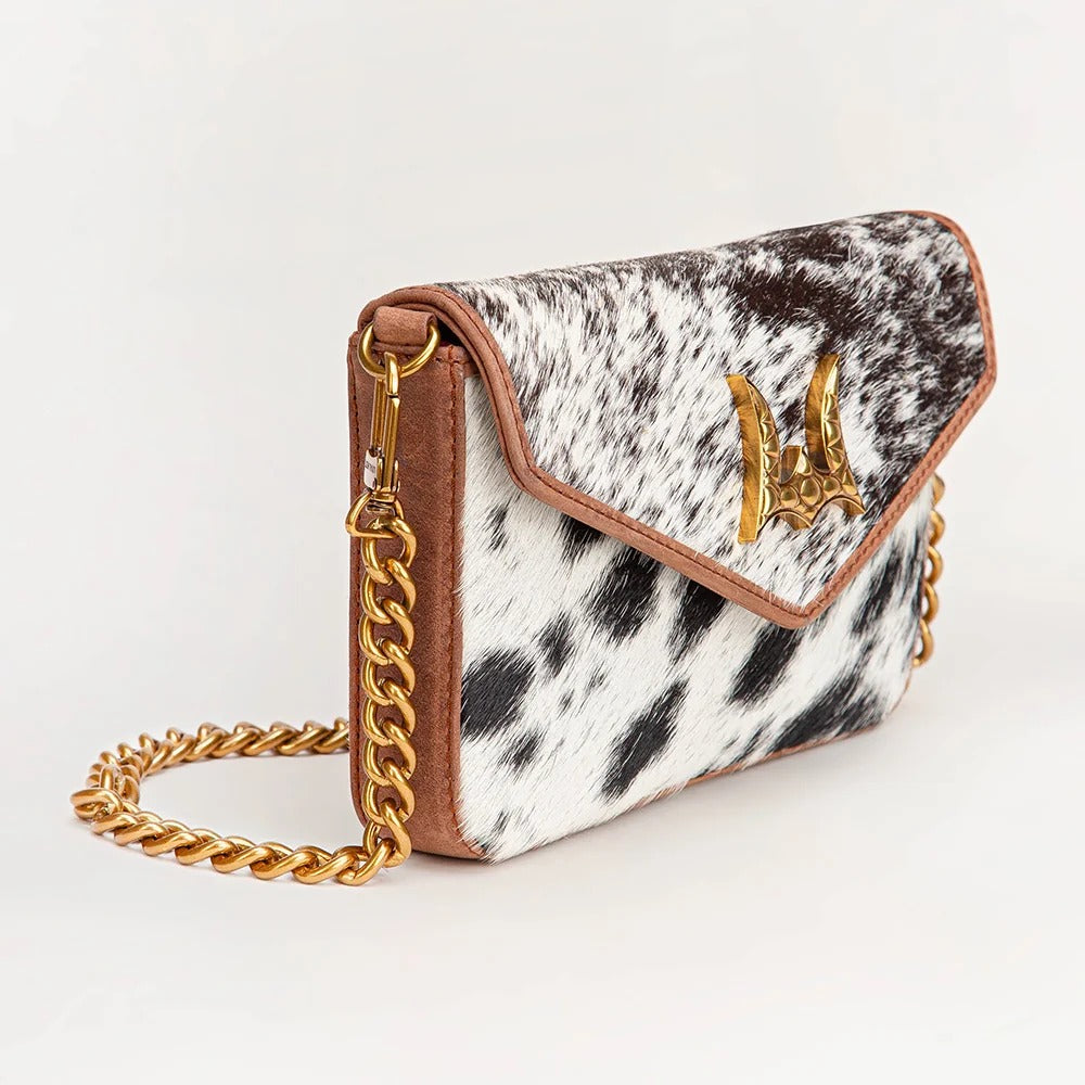 House of Hide genuine leather cow print handbag featuring a gold-tone chain strap on a light studio background