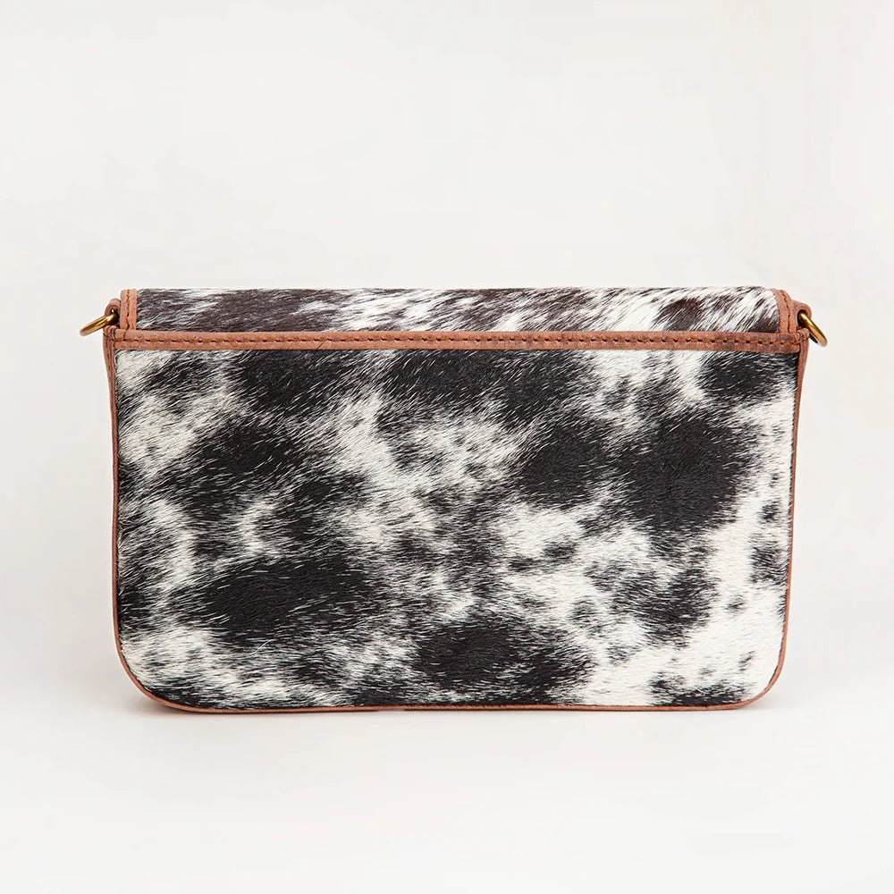 House of Hide genuine leather black and white cow print clutch bag featuring a western-inspired pattern on a light gray studio background