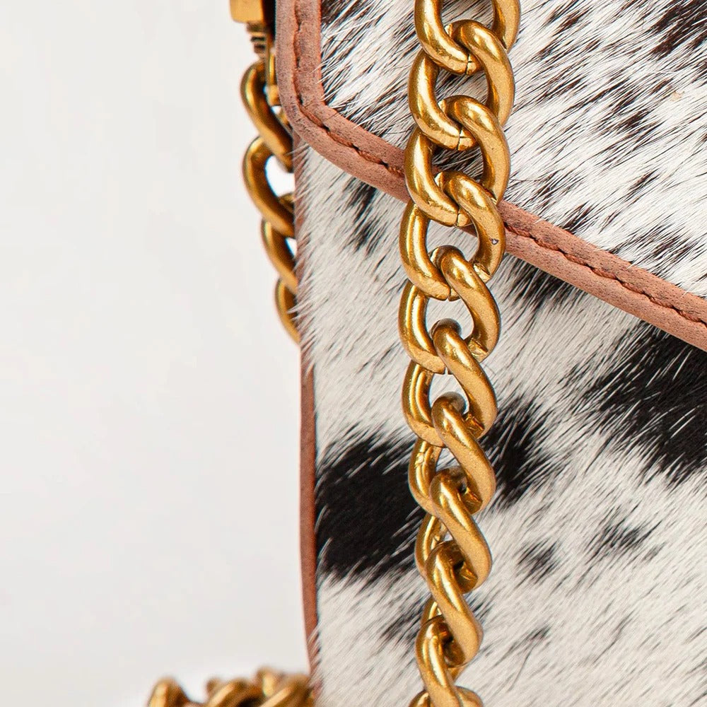 Close-up of a House of Hide genuine leather cowhide handbag featuring a detailed gold-tone chain strap and premium hardware