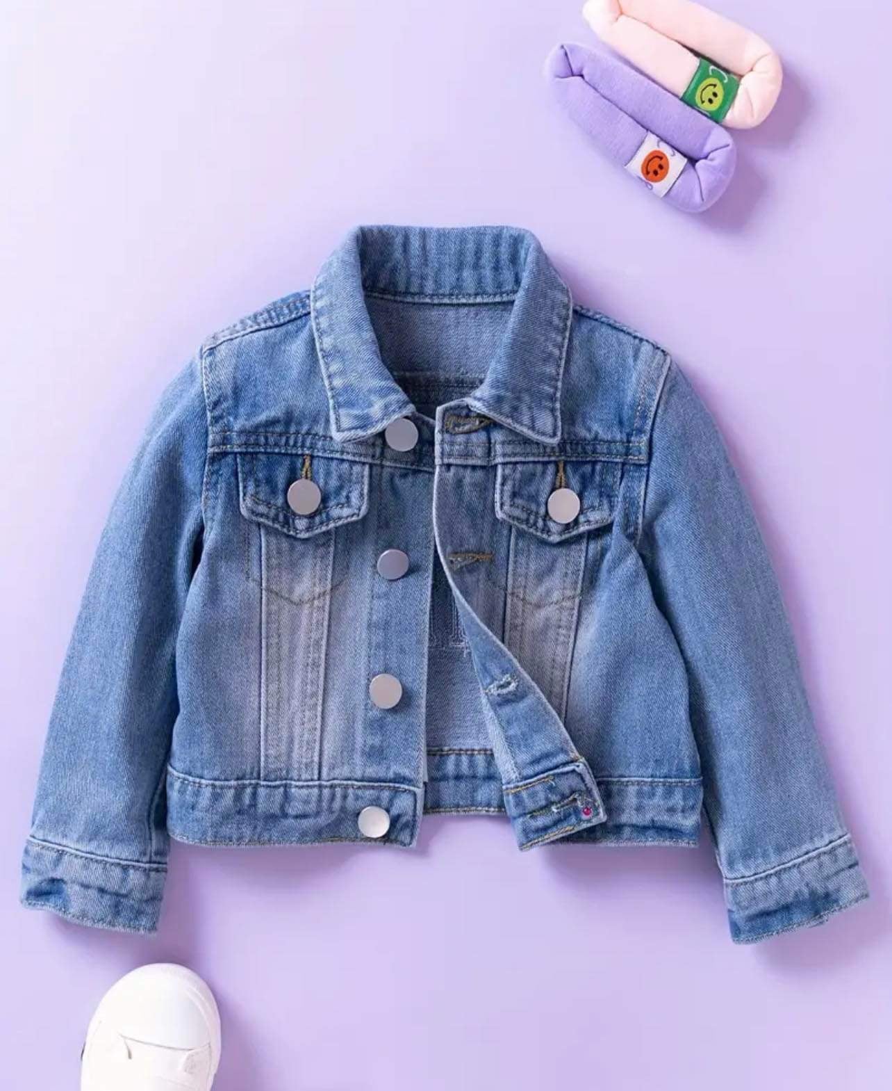 Mini denim jacket for toddlers with silver button details and soft blue fabric.