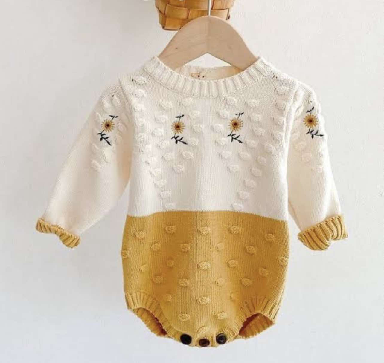 Mustard yellow and white baby romper with floral and dot details.