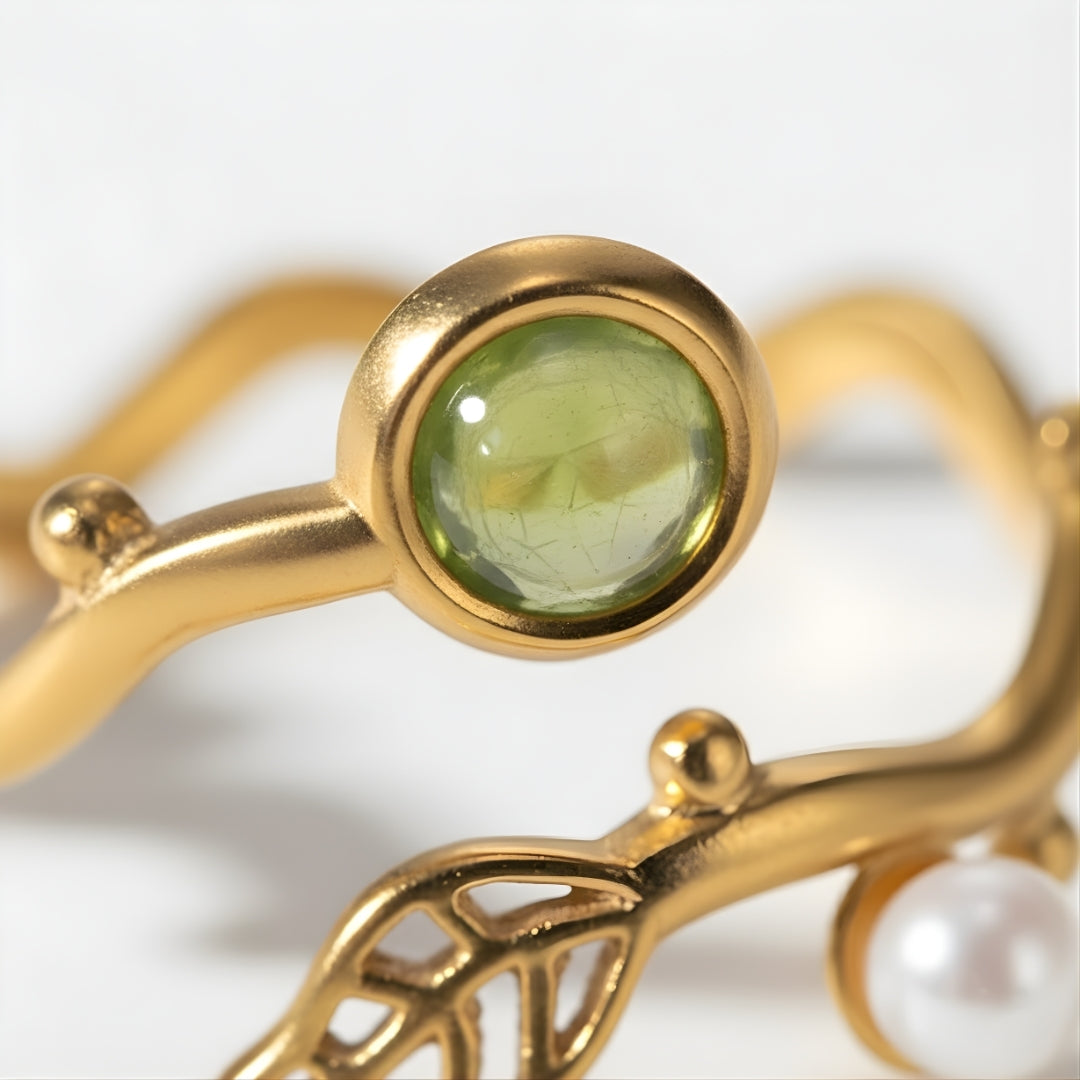 Close-up of the Pearl Leaf Harmony Ring showcasing a lustrous pearl, green gemstone, and golden leaf detail.