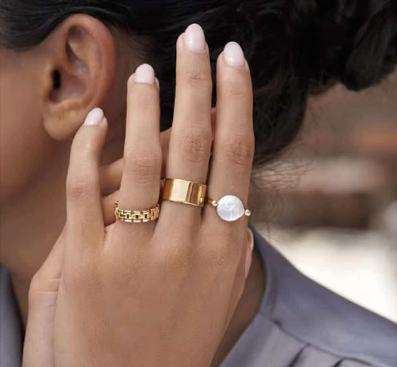 Close-up of Pearl Moon Ring featuring smooth U-shape band and mother-of-pearl accent in natural light.
