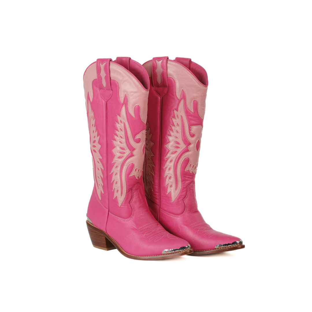 A pair of bright pink leather cowboy boots with light pink western-style embroidery and a brown stacked heel, shown against a plain white background.