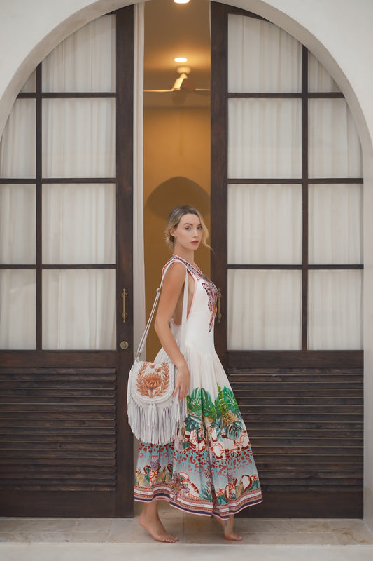 Protea Bloom Bag in off‑white leather with hand‑tooled floral design, fringe, and brass hardware. Crossbody with zip and magnetic closure. Ethically handmade.

