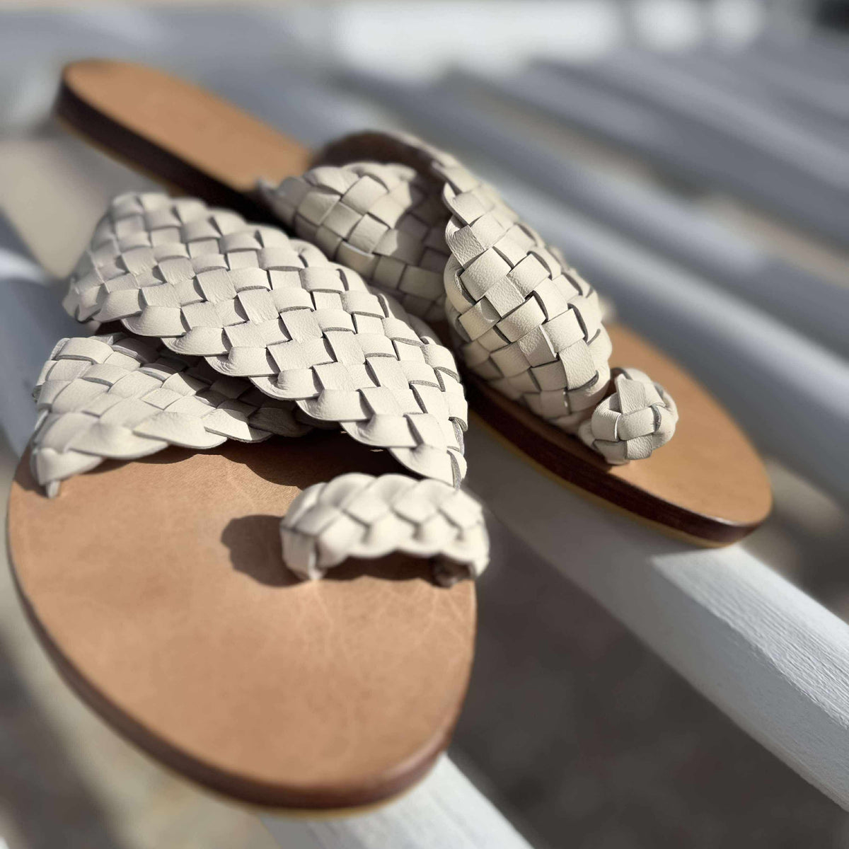 Pair of woven sandals on a white chair with a blurred background