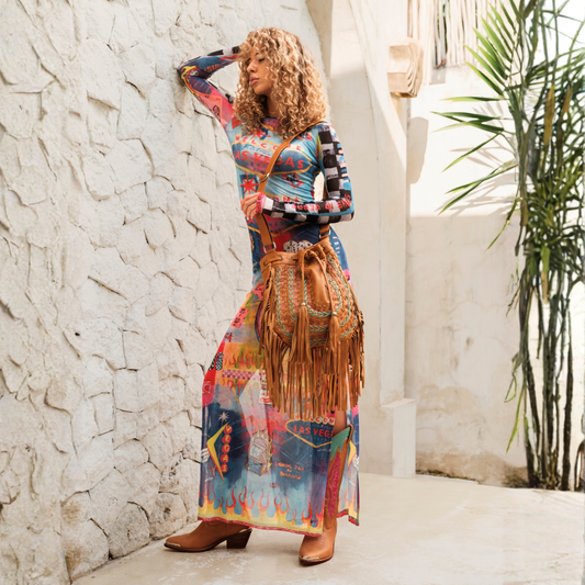 Sedona Drawstring Bag from House of Hide in brown leather with fringe detail being held by model in sunlit outdoor setting against textured white wall