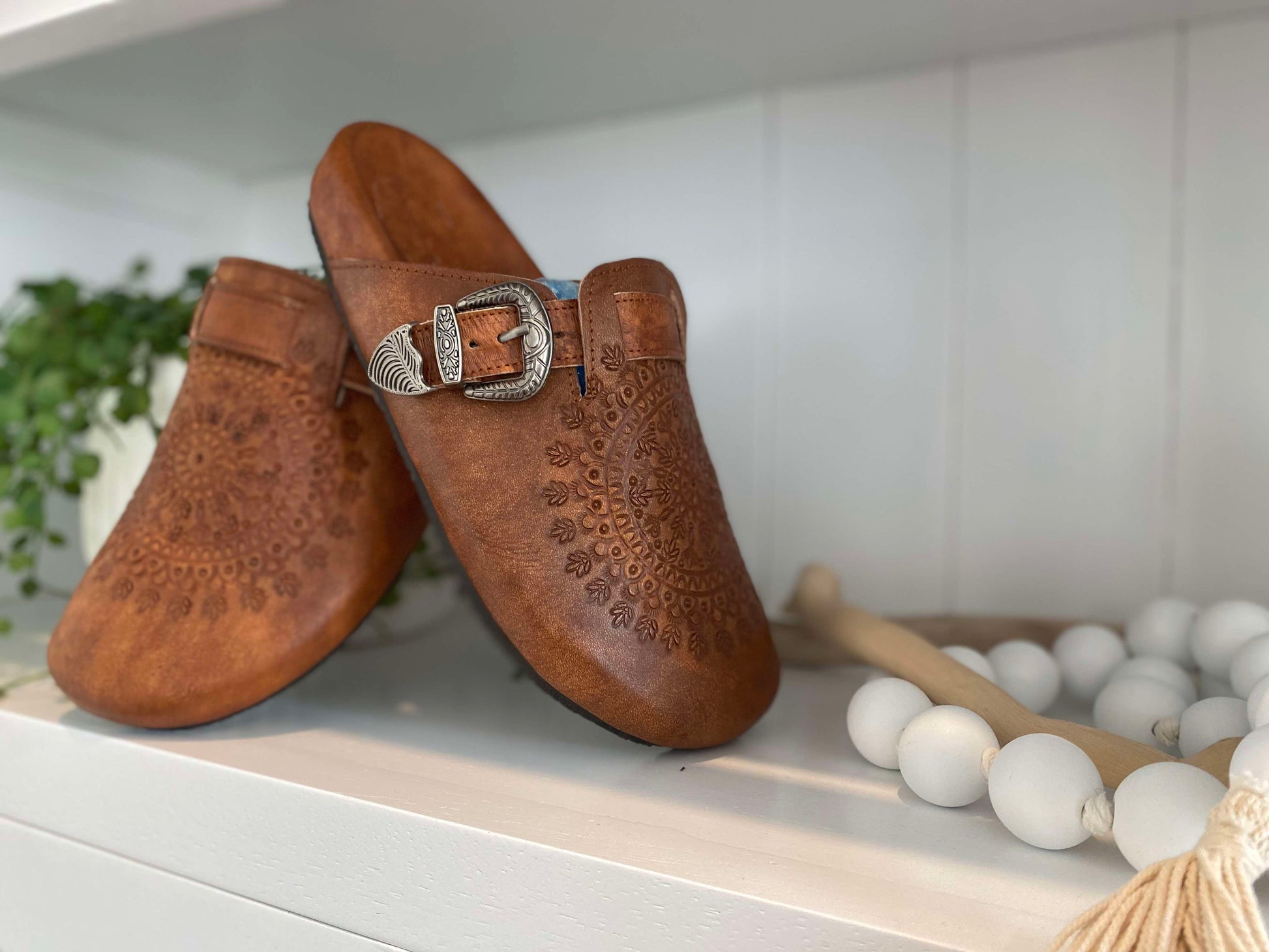 Side view of Western Buckle Boho Clogs. A stylish, hand-tooled brown leather mule with a round toe and vintage buckle design.