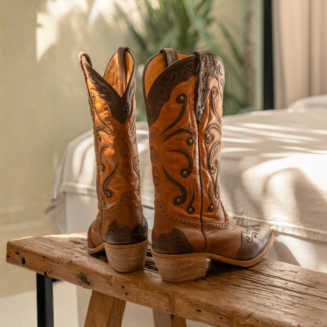 Woman wearing Sienna genuine leather cowboy boots in tan and brown featuring handcrafted Western detailing and a mid-calf silhouette.