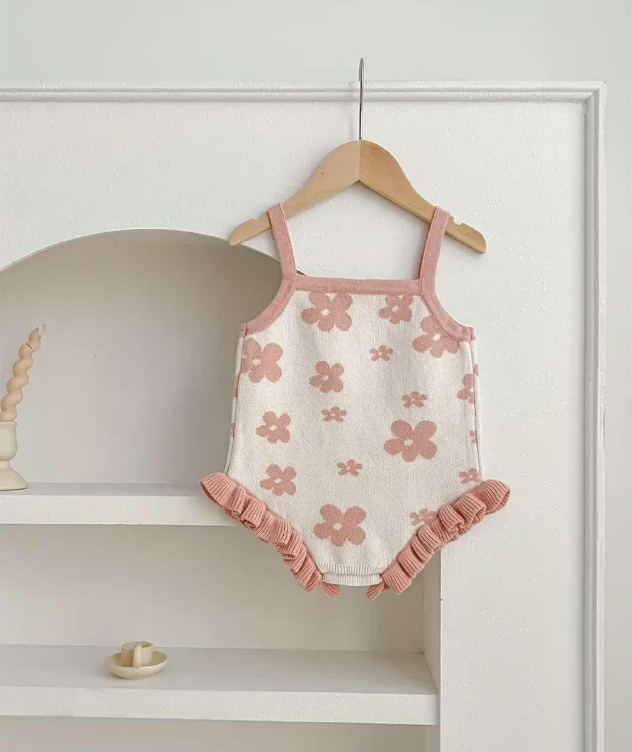 Size range display of floral knitted rompers in pink and beige, suitable for ages 3 months to 3 years.