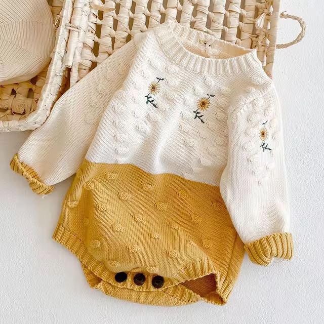 Sunflower knit baby romper in white and mustard yellow with long sleeves.