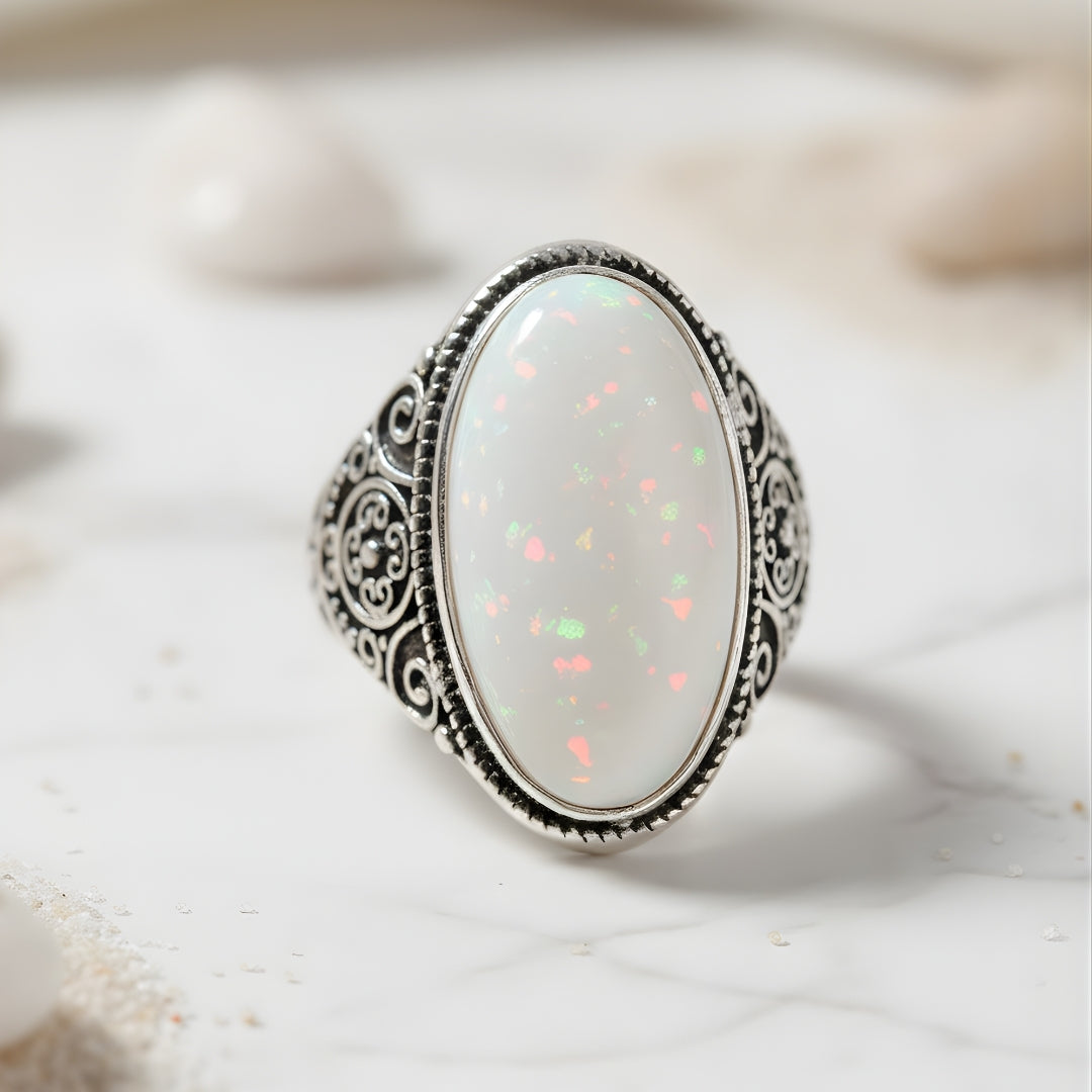 Tahitian Dawn silver ring with side engravings and white stone displayed on gray surface