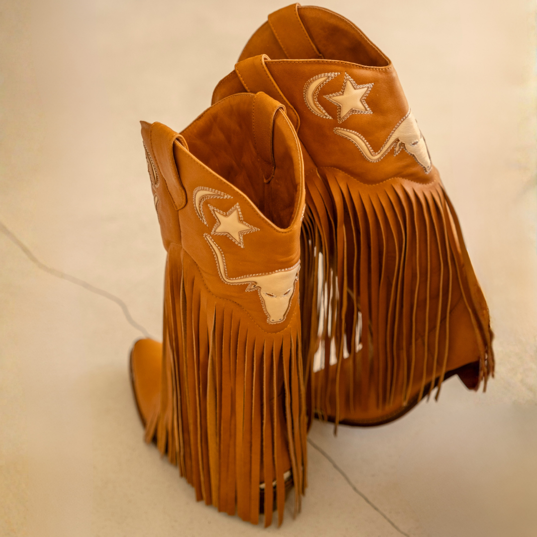 Tan leather Frontier Fringe cowboy boots by House of Hide with long Western fringe, pointed toe, stacked heel and embroidered celestial detailing.