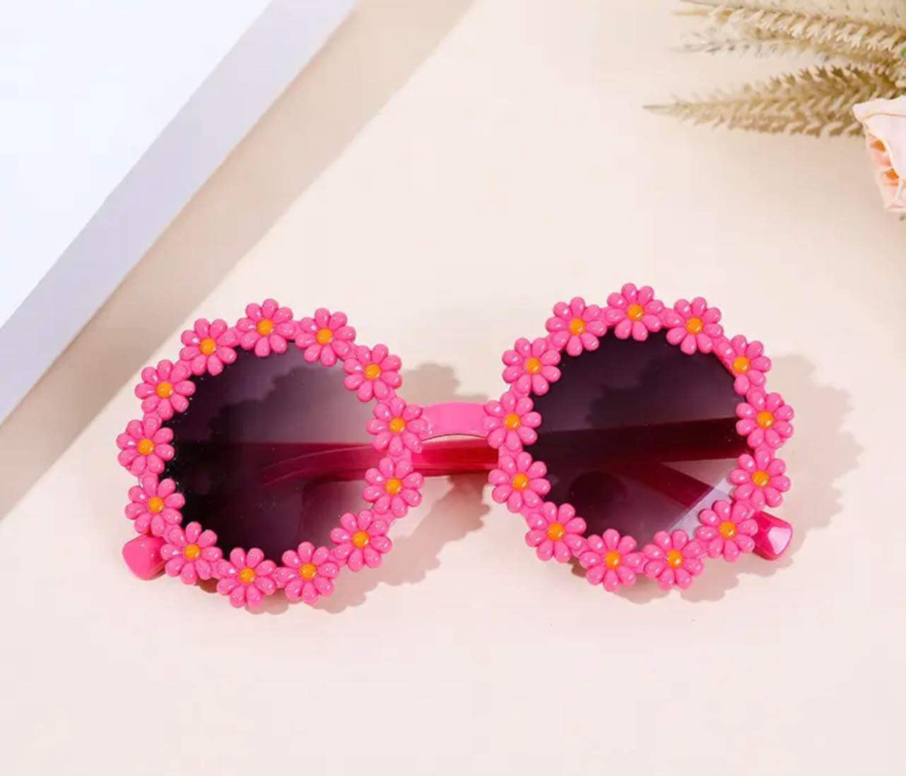 Toddler girl’s daisy sunglasses with playful pink flower petal design.