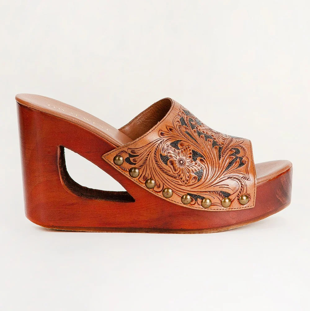 A single women's wedge mule sandal with a carved wooden platform and heel, featuring a tooled brown leather upper with floral scrollwork and brass-tone studs, shown on a plain light background.