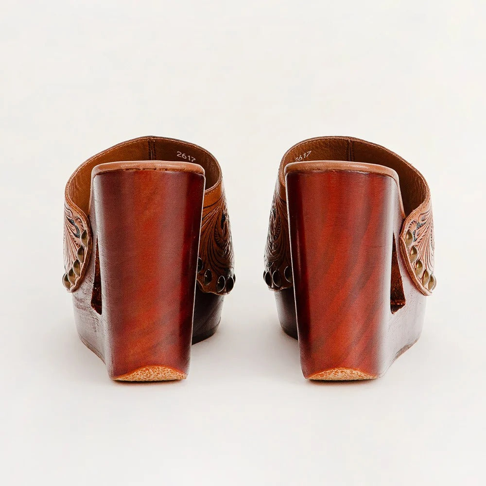 House of Hide genuine leather brown mule heels featuring carved floral detailing on the sides and stacked block heels, displayed from the back on a white background