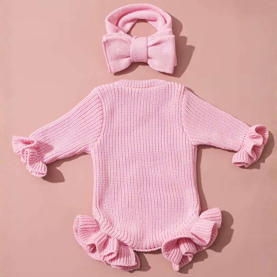 Welcome Baby Romper Set from House of Hide in soft pink ribbed knit with gentle stretch, hi I'm new here embroidery detail, ruffled trim at cuffs and leg openings, snap button closure, matching bow headband being styled for newborn announcement photos